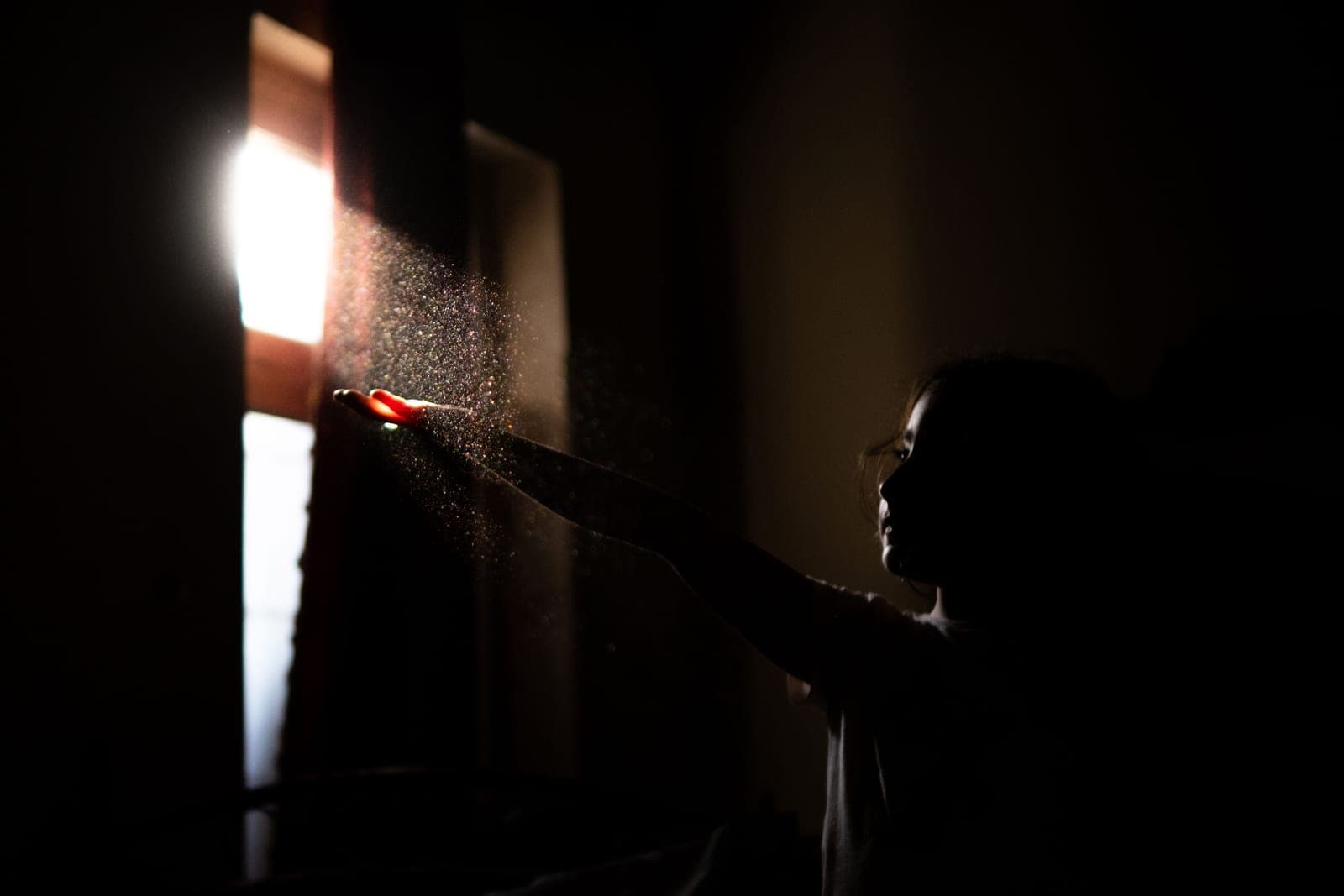 Morning light crossing a quiet bedroom, with dust visible in the beam